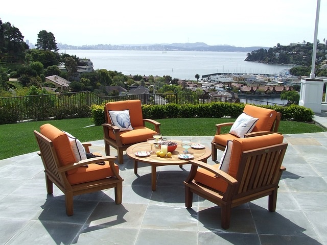 Terrassengestaltung im mediterranen Stil Bild zeigt Tisch mit 4 großen Stühlen auf Terrasse im Hintergrund Meeresbucht mit Hafen