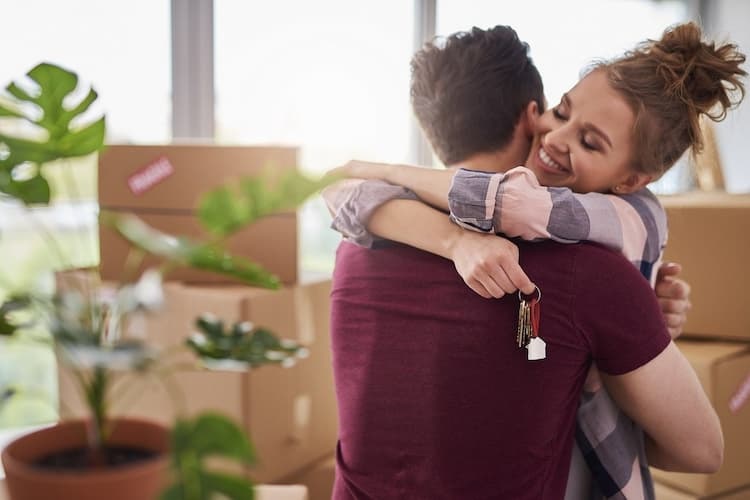 Wohnung mieten leicht gemacht: Bild zeigt glückliches Paar mit Wohnungsschlüssel vor Umzugkartons