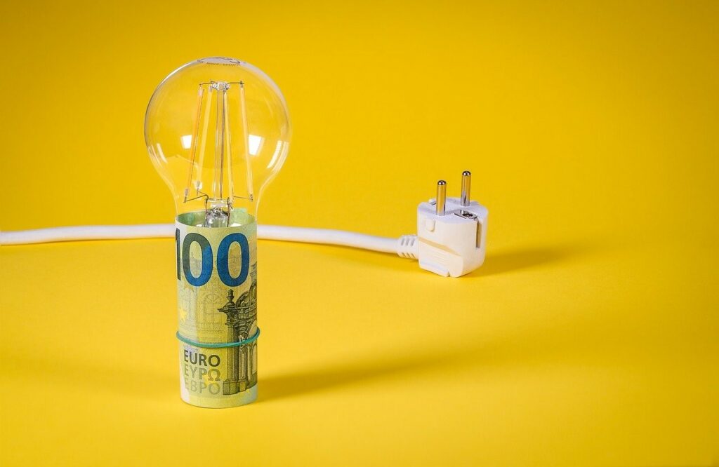 Energieautarkes Wohnen - Bild zeigt Glühbirne mit 100 Euro-Schein dahinter Stecker vor gelbem Hintergrund