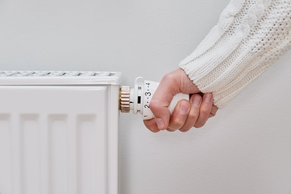 alles rund um die Gasheizung: Bild zeigt Hand, die am Thermostat eines Heizkörpers dreht